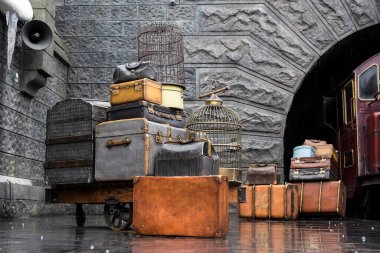 OSAKA, JAPONYA - 13 Mayıs 2017: Hogwarts Express treni, Universal Studio, Osaka, Japonya. Tren peronunda eski film aksesuarları, bavul, çanta, kuş kafesi.