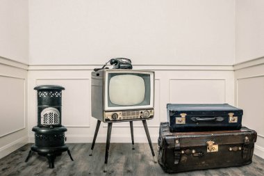 Kalorifer, televizyon ve bavullar rahat odada yerde.