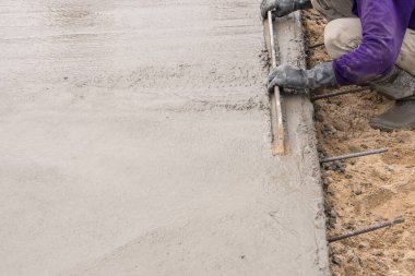 İnşaat işçisinin elleri beton zemini sıva ile kaplıyordu.