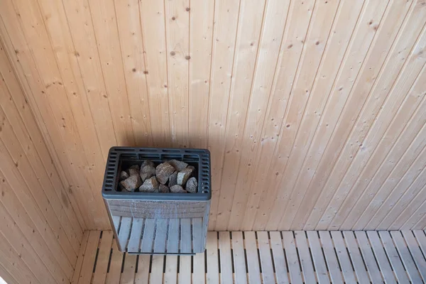 Sauna stone in heater on wooden interior wall