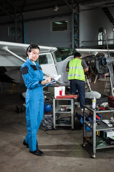 Young beautiful Asian lady inspecting the plane maintenance in garrage