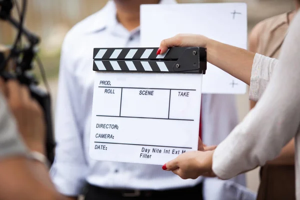 Female hands of movie crew holding clapperboard in the movie set