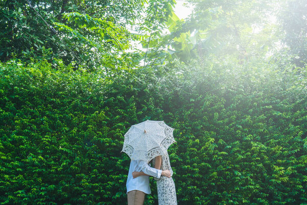 Asian couple kissing behind umbrella