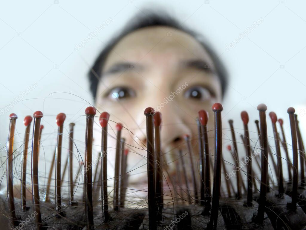 Close up photograph of hair falls on comb with blurry background of a man with worry expression