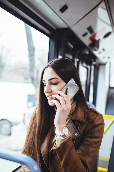 市バスで座っていると携帯電話で話している若い美人 — ストック写真