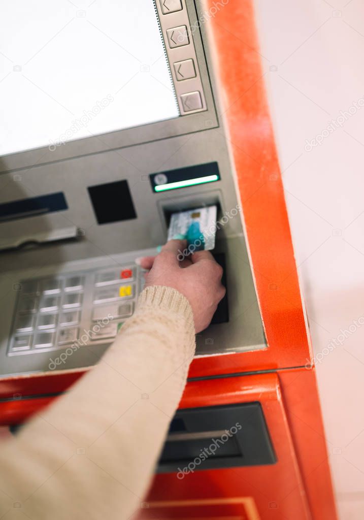 Young woman withdrawing money from credit card at ATM. Selective focus.
