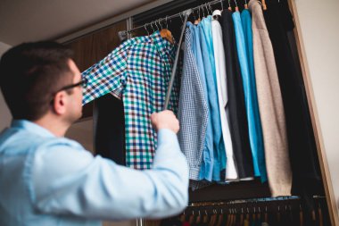 Genç adam gömlek gardırop seçme.