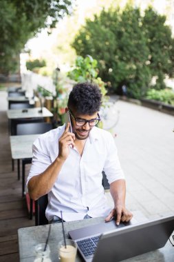 Bar bazı işlerini laptop ve cep telefonu alarak kafede oturan genç çekici afro Amerikalı iş adamı.
