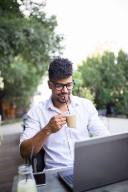 Genç yakışıklı Afro Amerikan oturma bina, kartvizit holding ve bazı işlerini laptop önünde büyük modern iş dostum. Seçici odak üstünde el.