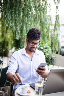 Genç çekici afro Amerikalı işadamı kafe barda oturmuş gülümseyen ve cep telefonu arıyorum. 