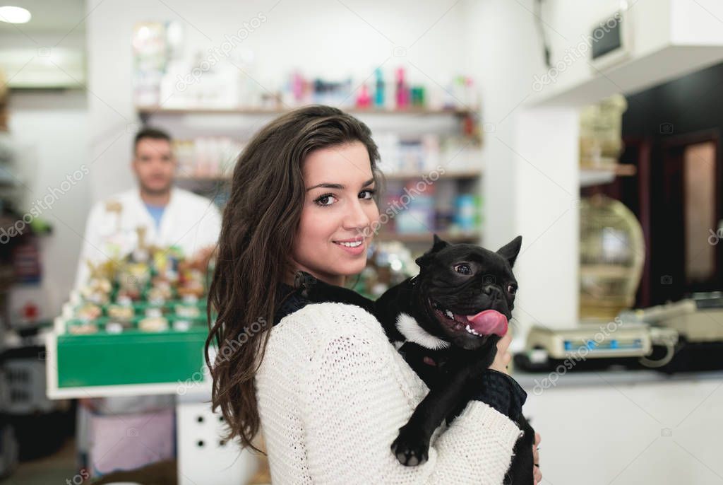 brunette woman with her French bulldog puppy in pet shop. 
