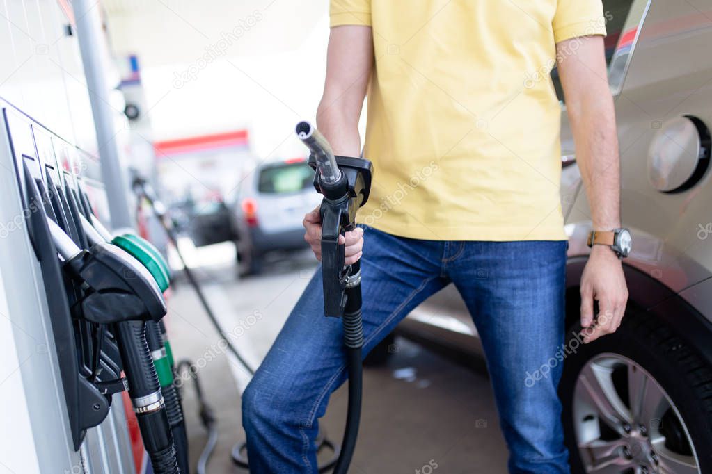 man filling gasoline fuel in car at gas station