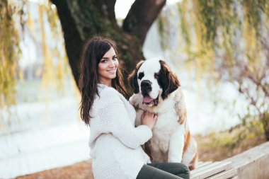 Parkta sevimli Saint Bernard köpeğiyle güzel, genç esmer kadın..