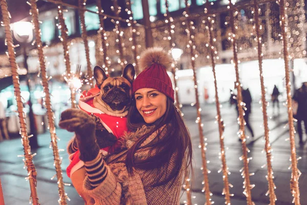 young  woman with French bulldog during Christmas eve on the street