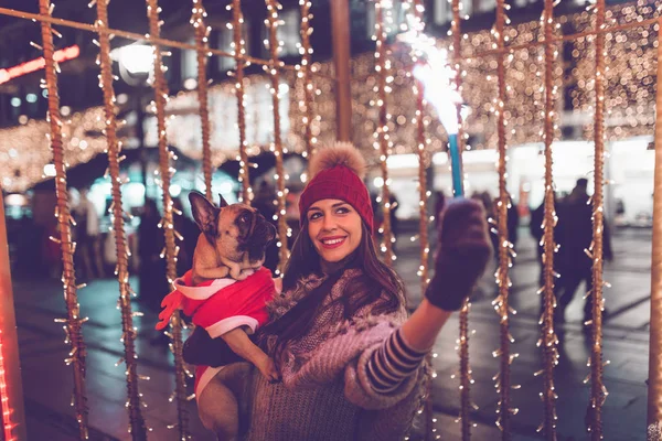 young  woman with French bulldog during Christmas eve on the street