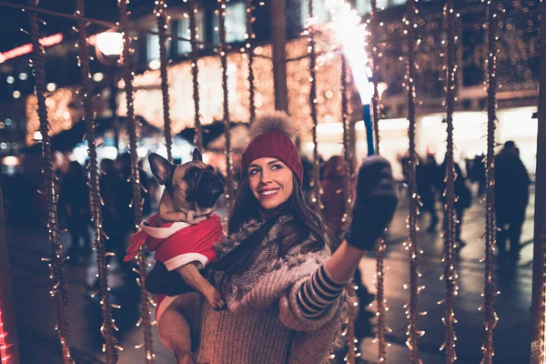 young  woman with French bulldog during Christmas eve on the street