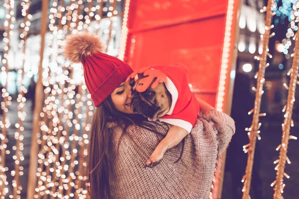 young  woman with French bulldog during Christmas eve on the street