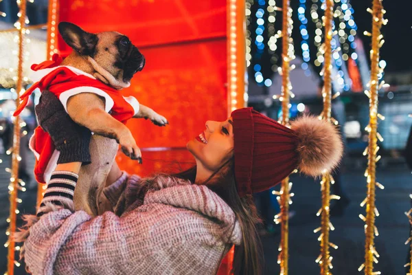 young  woman with French bulldog during Christmas eve on the street
