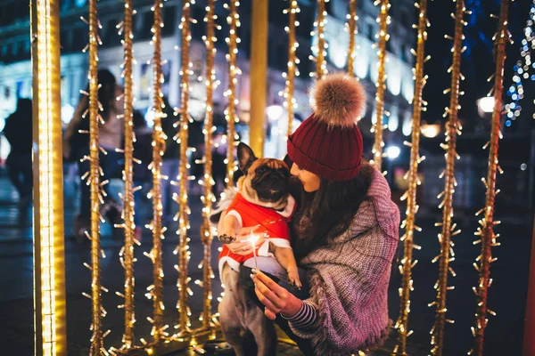 young  woman with French bulldog during Christmas eve on the street