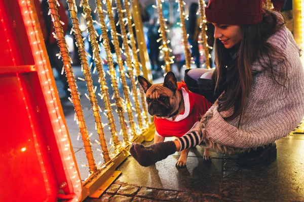 young  woman with French bulldog during Christmas eve on the street