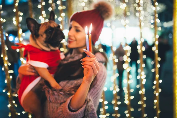 young  woman with French bulldog during Christmas eve on the street