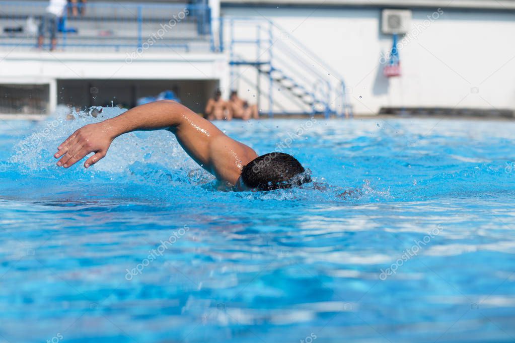  Young man swimming underwater and diving in the swimming pool.