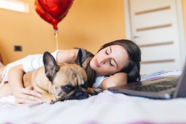 Çekici genç kadının ile onun Fransız bulldog evde beslenen hayvan yatak. 