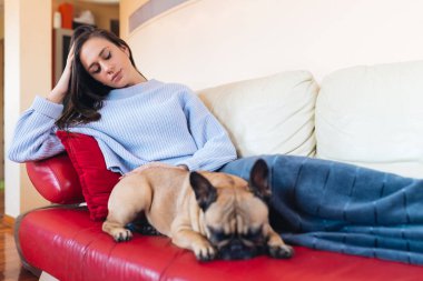 Çekici genç kadın kanepede onun Fransız bulldog evde beslenen hayvan ile yalan ve dinlenme. 