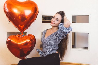 Kalp balonlar holding, poz ve kameraya bakıyor güzel, çekici esmer genç kadın.