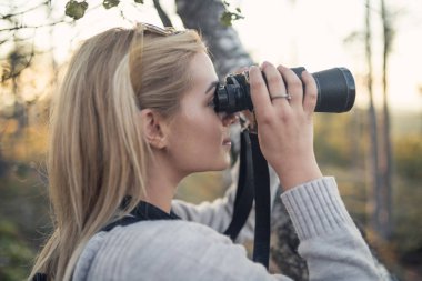 Güzel sarışın kadın dürbünle bakıyor ve muhteşem manzaraya ve günbatımına bakıyor..
