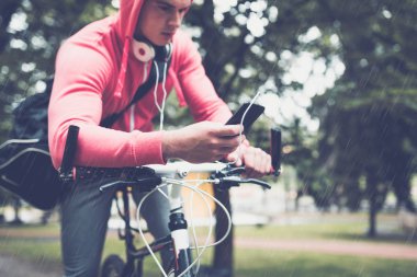 adam cep telefonu ararken bir parkta bisikletle