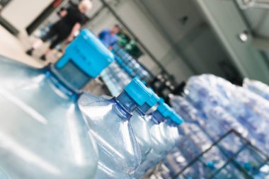 Bottling plant - Water bottling line for processing and bottling pure spring water into blue bottles. Selective focus.  clipart