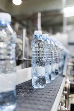 Şişeleme tesisi - Su şişeleme hattı saf kaynak suyunu işlemek ve şişelemek için mavi şişelere. Seçici odak. 