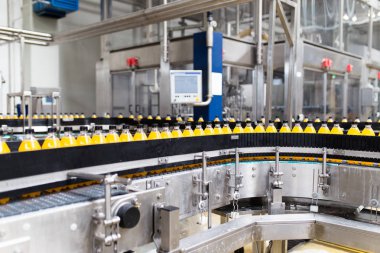 İçerideki sanayi fabrikaları ve makineler. Soda ve portakal suyu şişelerini işlemek ve şişelemek için robot fabrikası hattı.