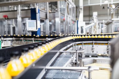 İçerideki sanayi fabrikaları ve makineler. Soda ve portakal suyu şişelerini işlemek ve şişelemek için robot fabrikası hattı.