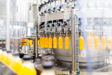 İçerideki sanayi fabrikaları ve makineler. Soda ve portakal suyu şişelerini işlemek ve şişelemek için robot fabrikası hattı.