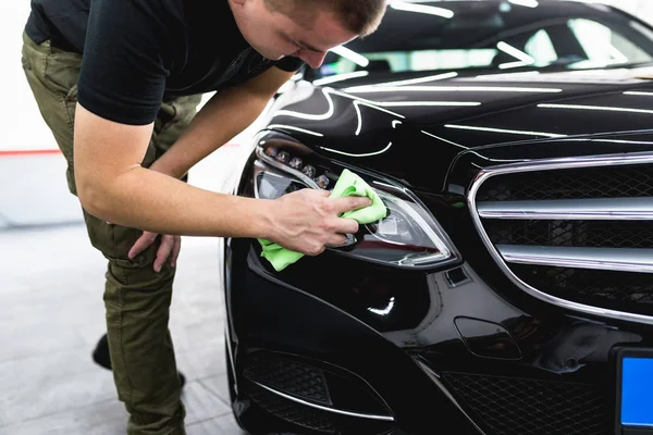 A man cleaning car with microfiber cloth, car detailing (or valeting) concept. Selective focus.