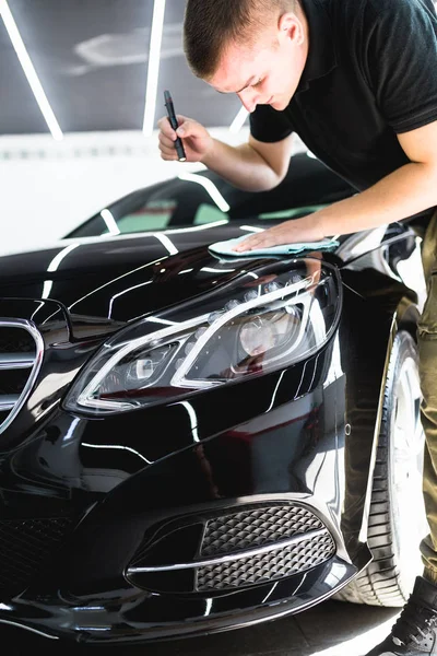 A man cleaning car with microfiber cloth, car detailing (or valeting) concept. Selective focus.