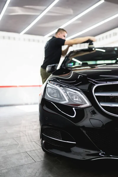 Car detailing - Worker with orbital polisher in auto repair shop. Selective focus.