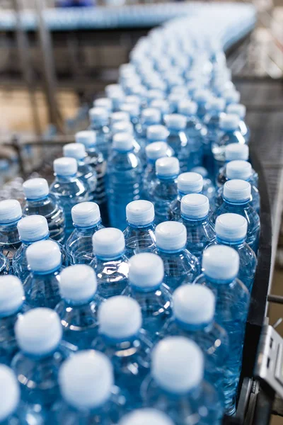 Şişeleme tesisi - Su şişeleme hattı saf kaynak suyunu işlemek ve şişelemek için mavi şişelere. Seçici odak. 