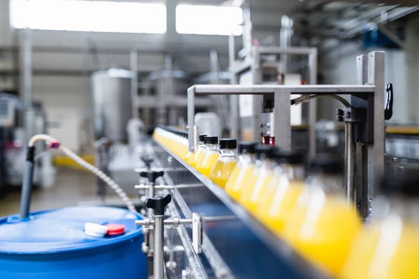 Industrial factory indoors and machinery. Robotic factory line for processing and bottling of soda and orange juice bottles.