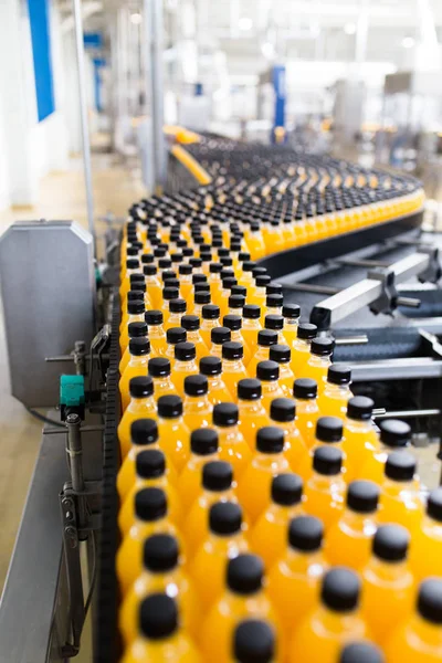 Industrial factory indoors and machinery. Robotic factory line for processing and bottling of soda and orange juice bottles.