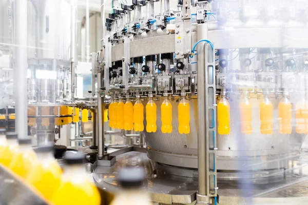 Industrial factory indoors and machinery. Robotic factory line for processing and bottling of soda and orange juice bottles.