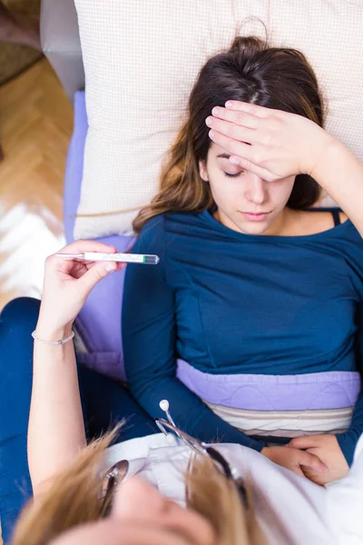 Doktor hastasını ev koşullarında sıcaklığını kontrol tıbbi üniformalı