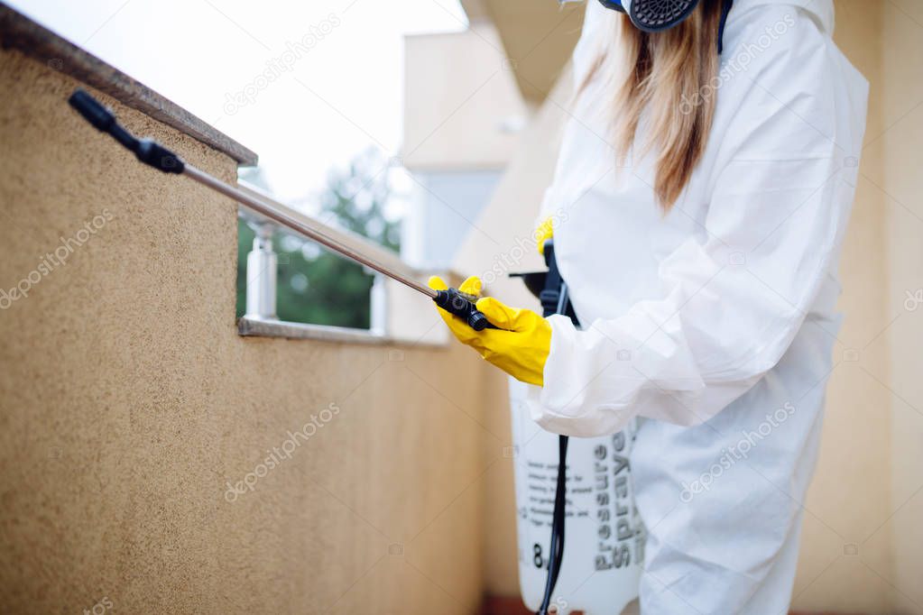 Exterminator in work wear spraying pesticide with sprayer
