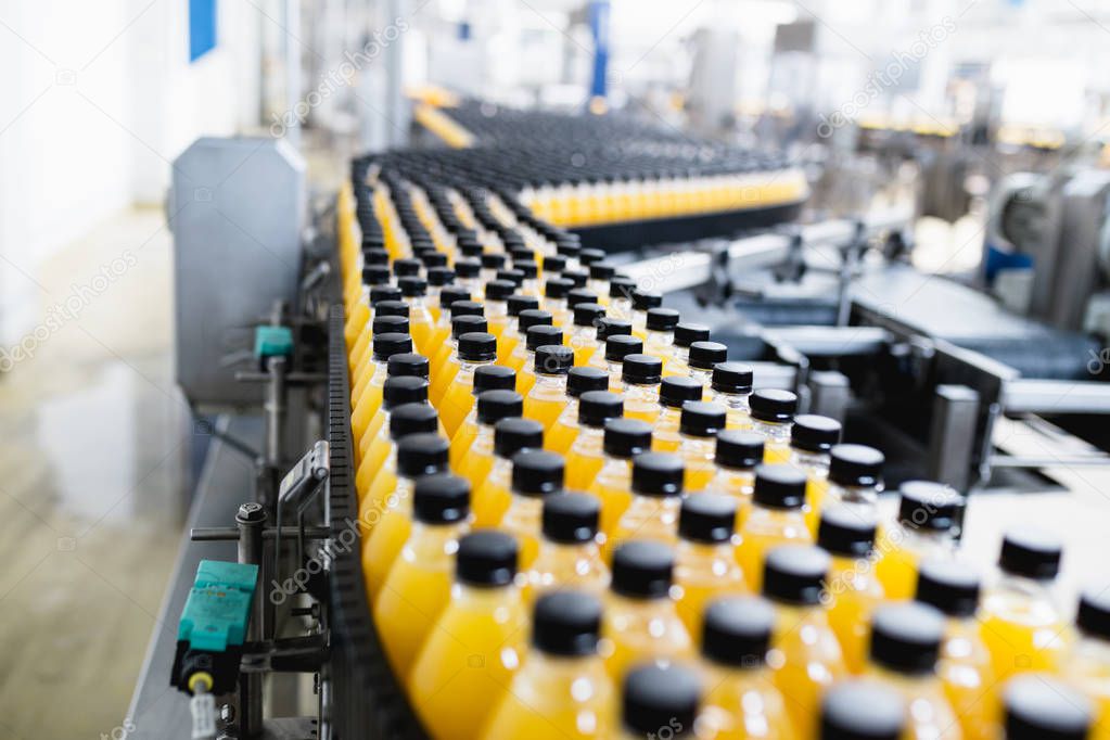 Industrial factory indoors and machinery. Robotic factory line for processing and bottling of soda and orange juice bottles.