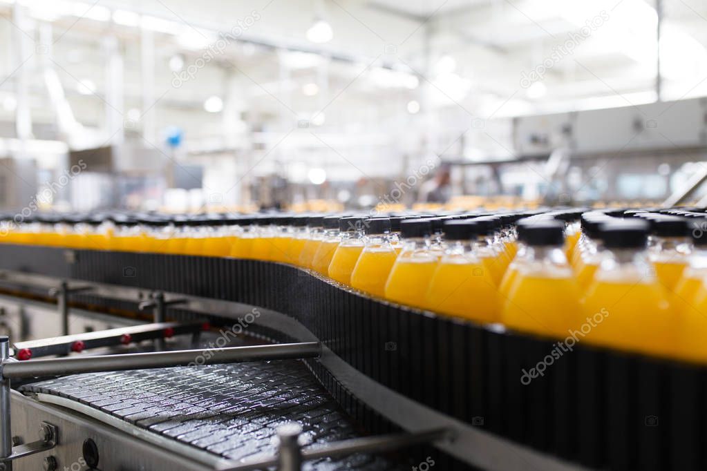 Industrial factory indoors and machinery. Robotic factory line for processing and bottling of soda and orange juice bottles.
