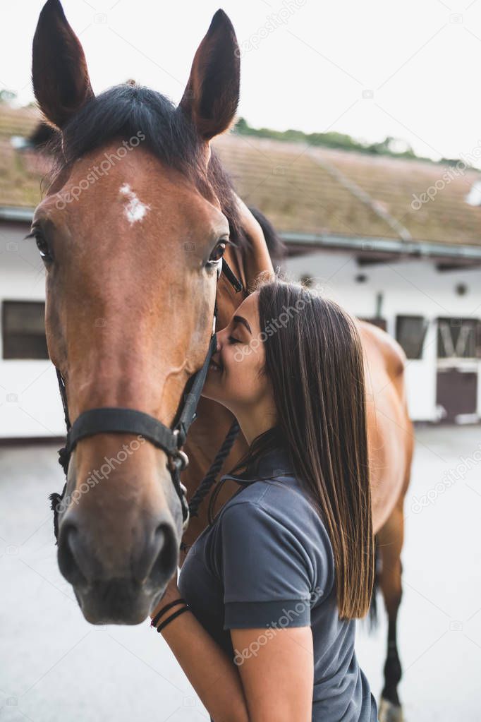 Beautiful brunette girl kissing her horse. Selective focus