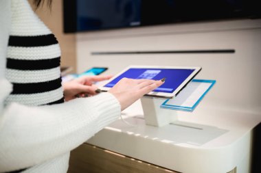 içinde hareket eden alışveriş kadın ve dükkanı ve seçimi bir sonraki model onun için tablet. Seçici odak üstünde el.