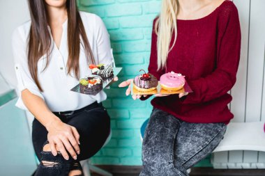 İki güzel genç kadın lezzetli tadını sırlı ve donuts dekore edilmiş. 